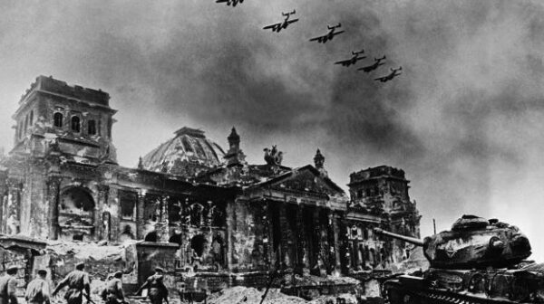 In this composite image by Yevgeny A. Khaldei (March 23, 1917 - October 6, 1997), the renowned photographer has seven Petlyakov Pe-2 dive bombers overflying the Reichstag while Red Army soldiers rush the building supported by a Josef Stalin IS-2 tank. There are at least four separate images in this composite. The Reichstag is one; the original has a destroyed bus in the lower left, which was covered by the onrushing Red Army squad. The squad is likely a staged reenactment, possibly taken on May 4 when photographer Ivan M. Shagin (1904-1982) also photographed the reenactment. The Petlyakov Pe-2 aircraft appear to be the same aircraft duplicated seven times. The IS-2 tank is significant, not only because it is named after Stalin; IS-2 tanks, attached as one heavy tank brigade to each of the Soviet Fronts (Army Group). Later enough IS-2s were produced so that each tank corps had an IS-2 regiment with twenty-one tanks. The IS-2 was reserved for storming fortifications, in concert with combat engineers. It could engage German Tiger I and II tanks, although the Tiger's 88mm (3.46 inch) gun could outrange the IS-2's 122mm (4.8 inch) gun. The composite photo was often used by Soviet photographers, who did not have any ethical issues with manipulating images. Khaldei himself made several other composite images during the war.